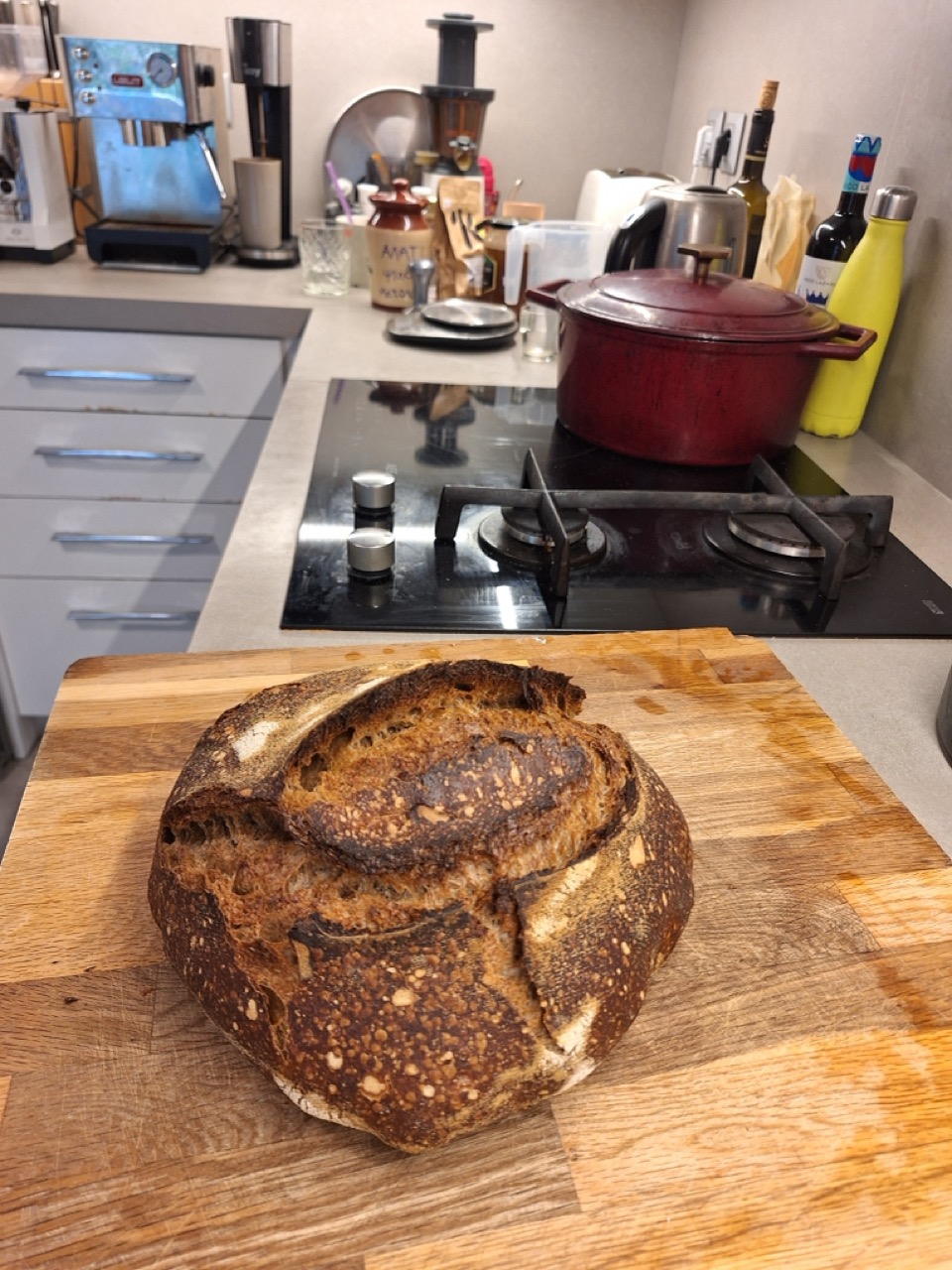 Dark-crusted sourdough loaf on a board in the kitchen
