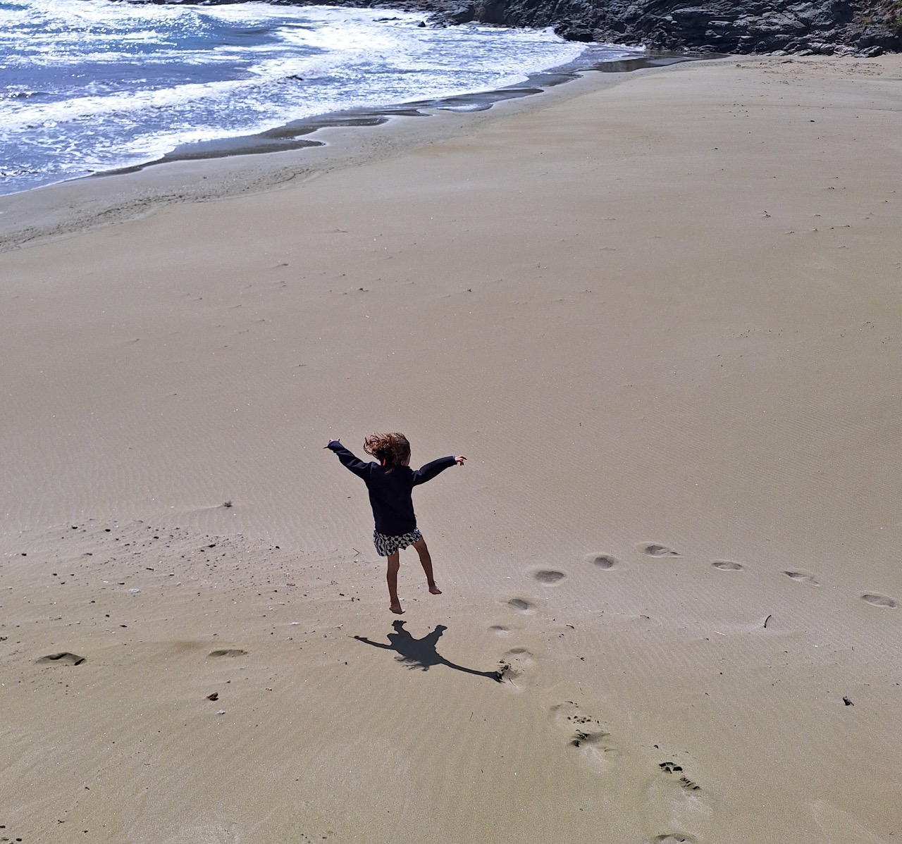 Child jumping on Tinos beach