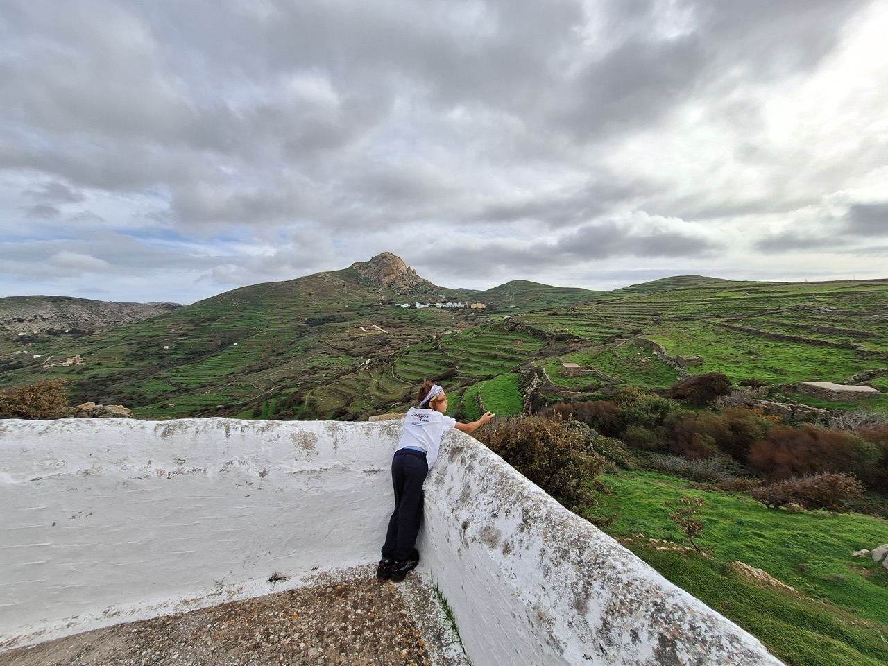 Child looking out over the green terraced hills of Tinos