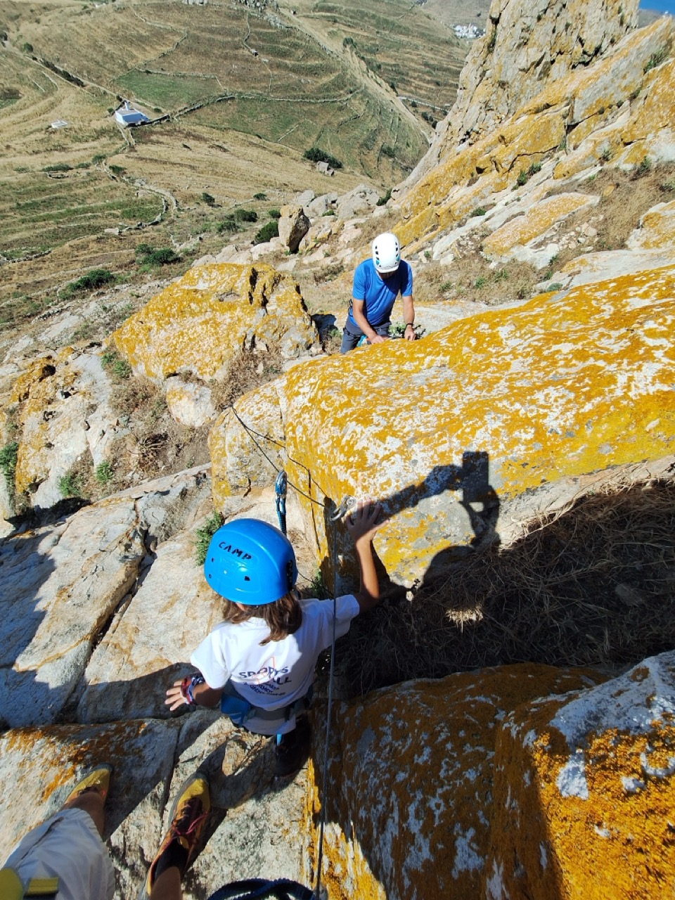 George traversing the via ferrata above Exomvourgo, Tinos, with the Aegean stretching behind him